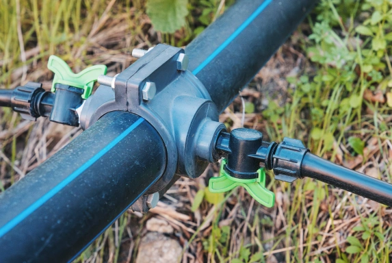 "Professional drip irrigation components with black tubing and green valves in a garden setting"